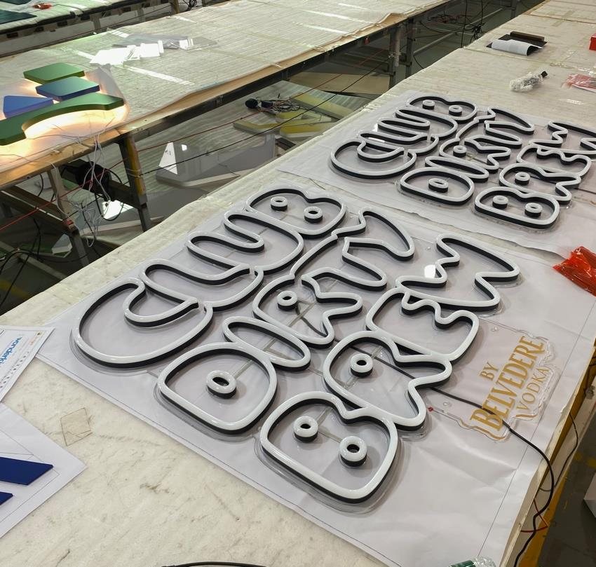 Club Dirty Brew lettering, cut and laid out on the bench with the Belvedere Vodka sign