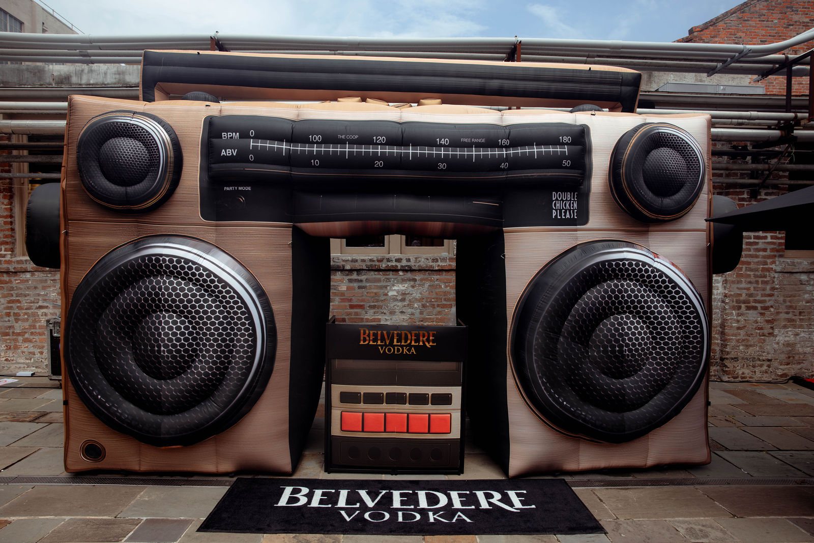 The giant inflatable boombox straight on: two speaker cones, the tuner, the cassette bay with the Belvedere DJ booth inside, and a Belvedere floor mat