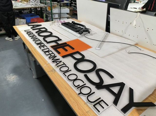 The La Roche-Posay Laboratoire Dermatologique dimensional letters laid out on a bench before install