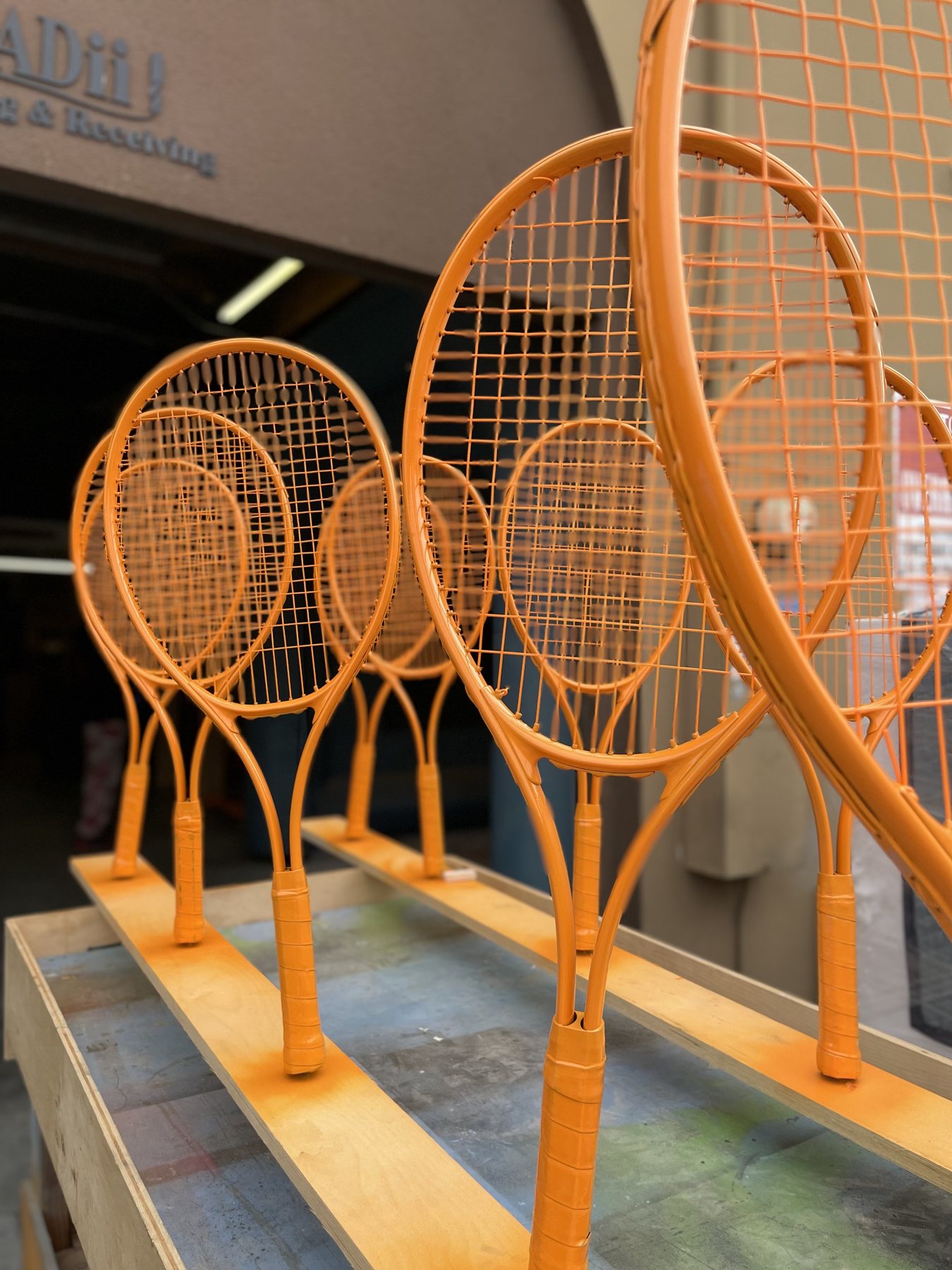 Tennis rackets painted orange and mounted upright on a wooden base