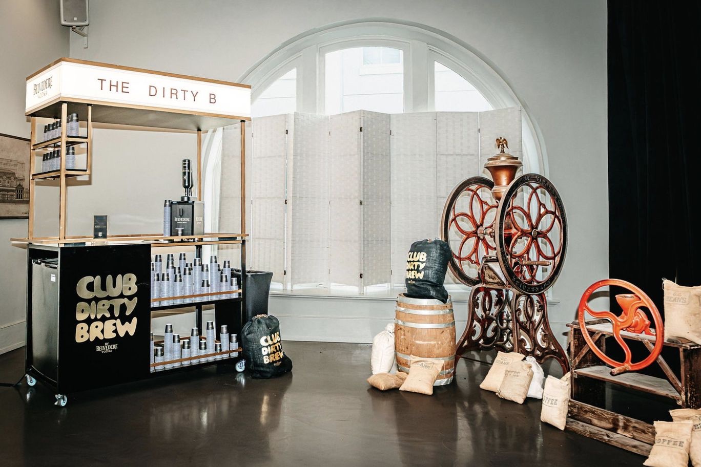 The cart in the event room with a barrel, two antique coffee grinders and burlap sacks beside it